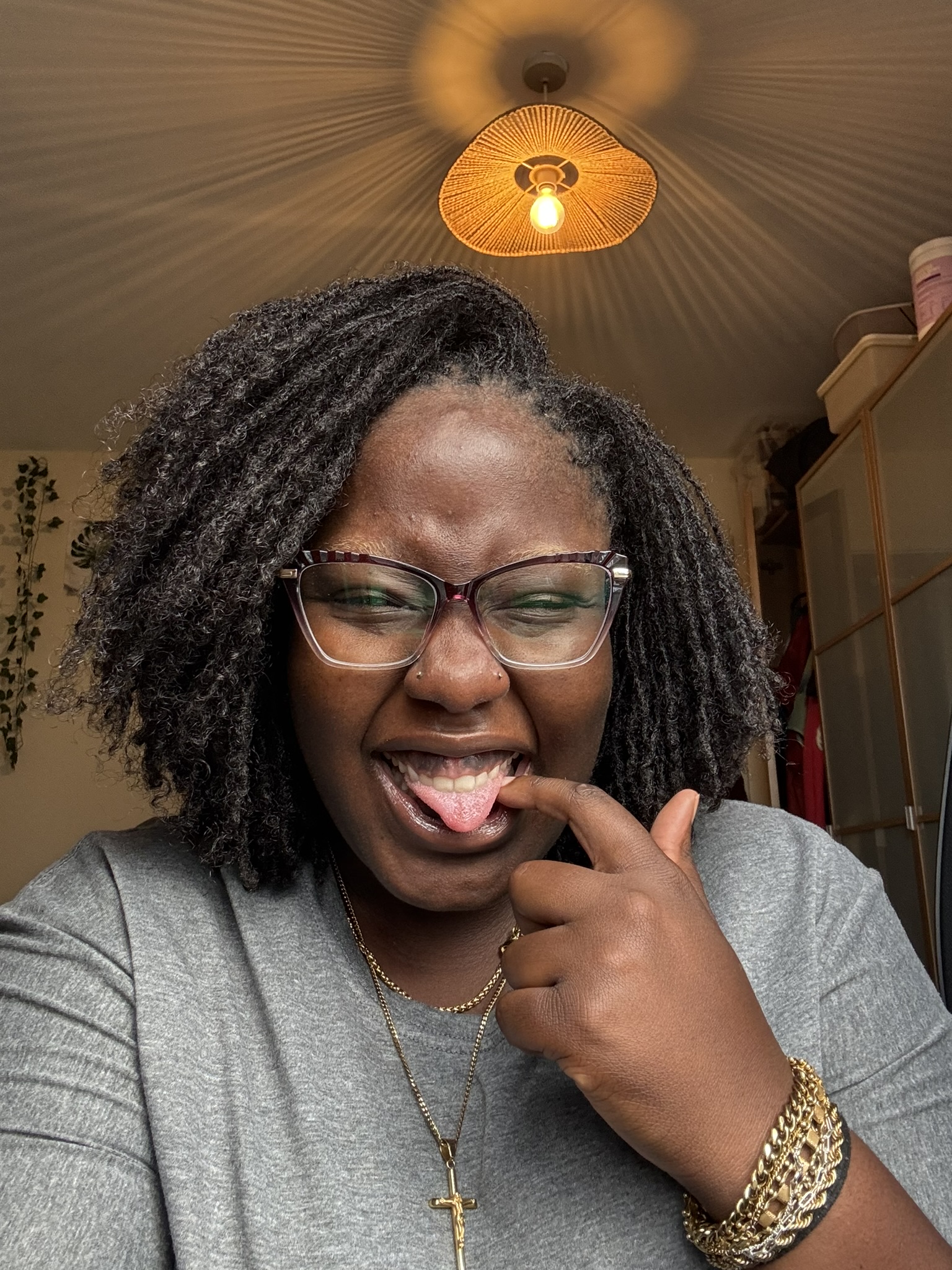 Osayi pulling a cheeky face under a woven pendant lamp